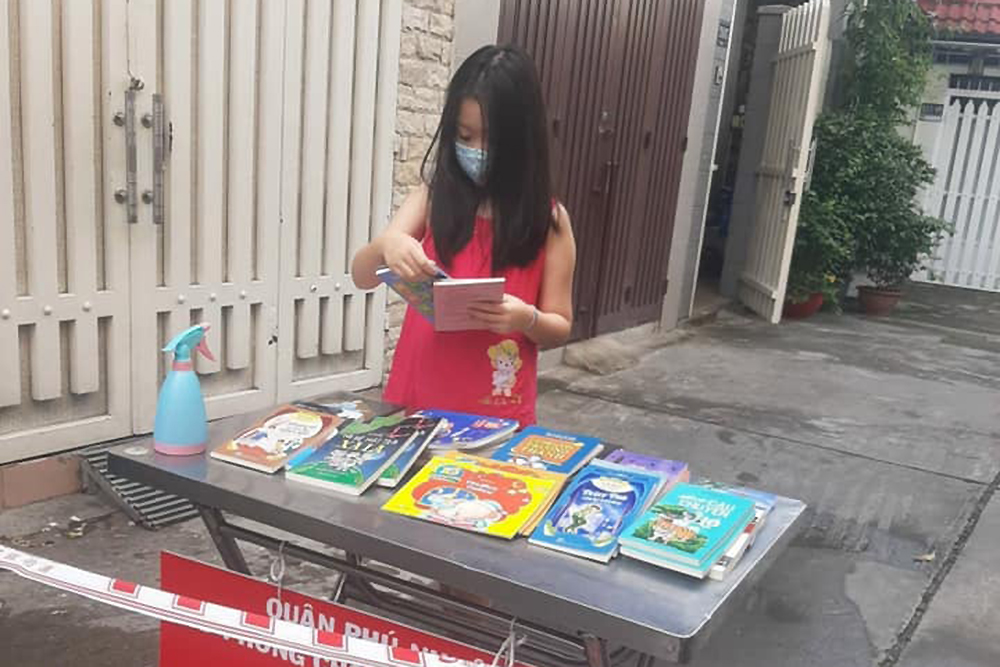Một độc giả nhí ở phường 8, quận Phú Nhuận lựa truyện trên bàn sách ở khu phong tỏa. Ảnh: NXB Tổng hợp TP HCM.